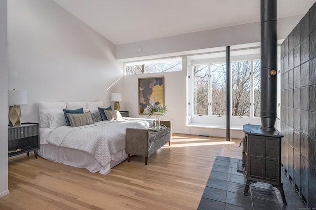 bedroom featuring a wood stove and light hardwood / wood-style flooring