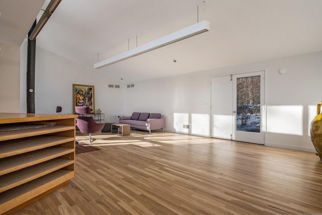 living room with a wood stove, light hardwood / wood-style flooring, and high vaulted ceiling