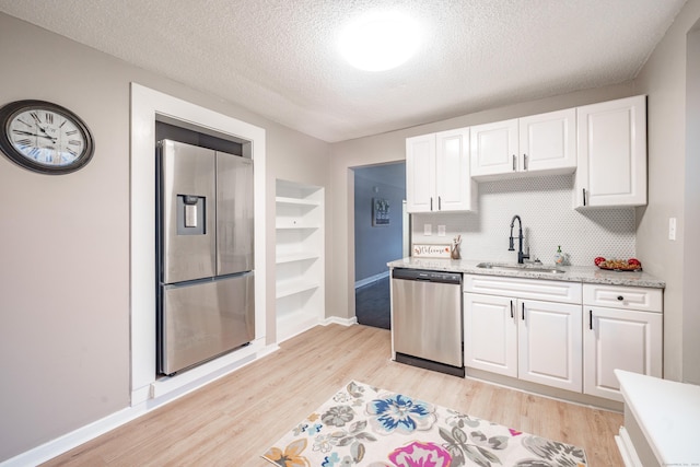 kitchen with sink, light hardwood / wood-style flooring, a textured ceiling, appliances with stainless steel finishes, and white cabinetry