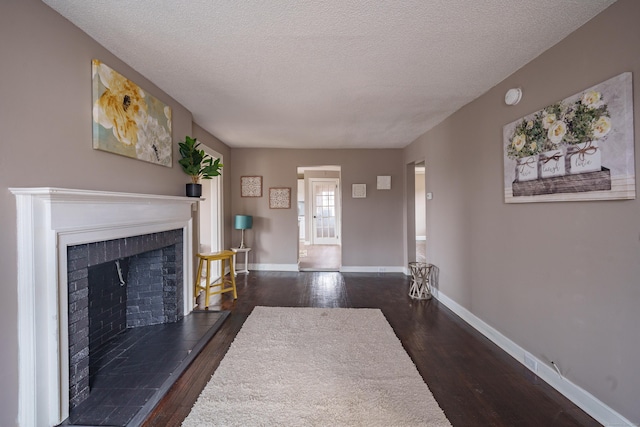 unfurnished living room featuring a textured ceiling, a tiled fireplace, and dark hardwood / wood-style floors