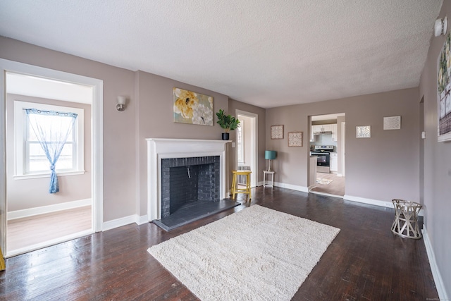 living room featuring dark hardwood / wood-style flooring, a textured ceiling, and a brick fireplace