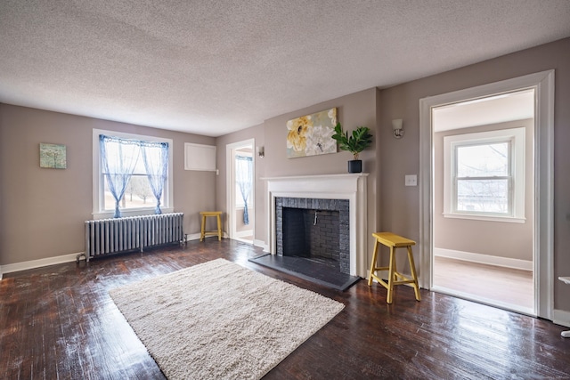 living room with dark hardwood / wood-style floors, a healthy amount of sunlight, a textured ceiling, and radiator