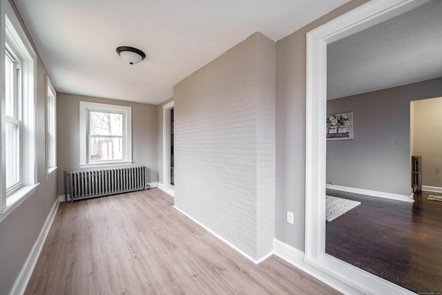 unfurnished room featuring a textured ceiling, light hardwood / wood-style flooring, and radiator