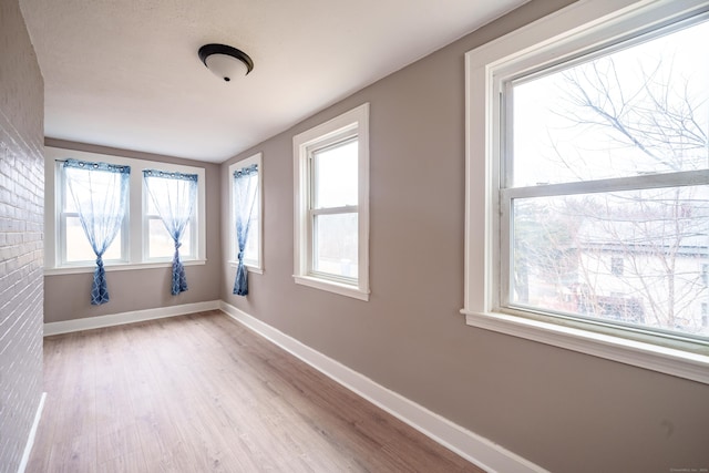 empty room featuring light wood-type flooring and brick wall