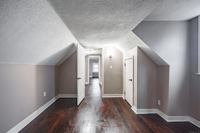 bonus room featuring dark hardwood / wood-style flooring, a textured ceiling, and vaulted ceiling