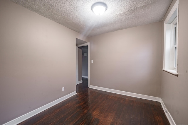 empty room featuring dark hardwood / wood-style floors and a textured ceiling