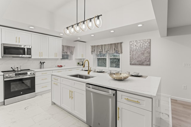 kitchen with sink, white cabinetry, light stone counters, a center island with sink, and appliances with stainless steel finishes