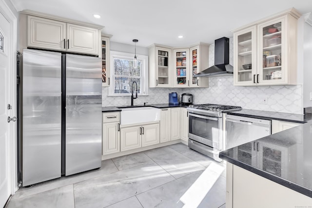 kitchen featuring backsplash, wall chimney range hood, hanging light fixtures, sink, and appliances with stainless steel finishes