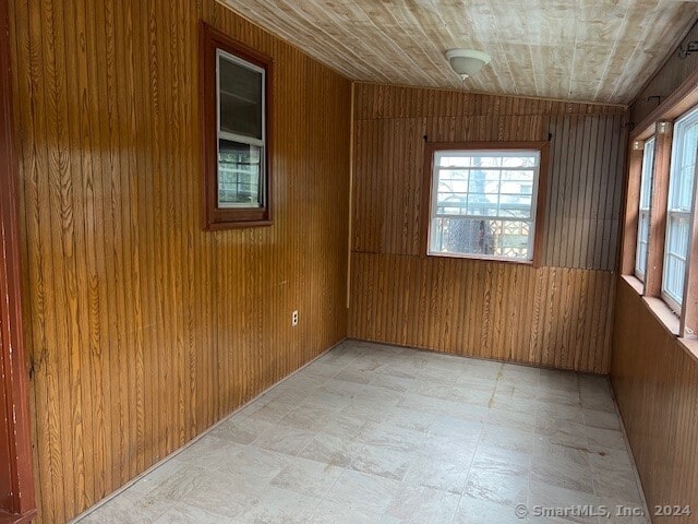 unfurnished room featuring wood ceiling and wood walls