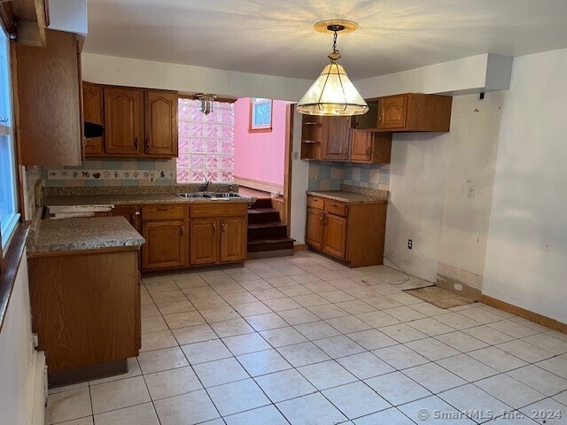 kitchen with backsplash, sink, light tile patterned floors, and hanging light fixtures