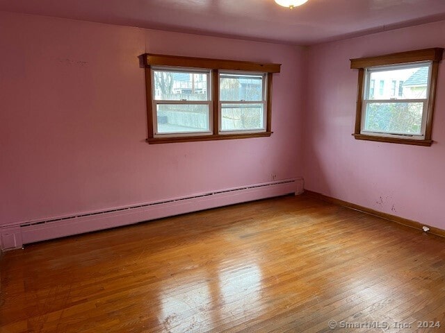 empty room featuring hardwood / wood-style flooring and a baseboard heating unit