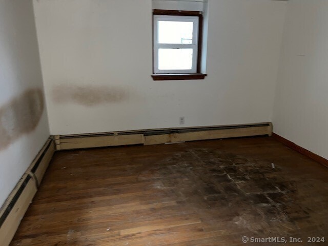 empty room with a baseboard radiator and dark wood-type flooring