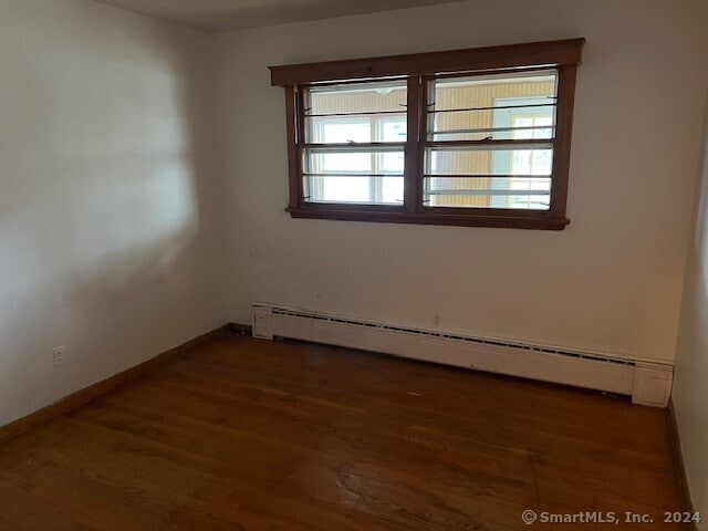 empty room featuring dark hardwood / wood-style floors and baseboard heating