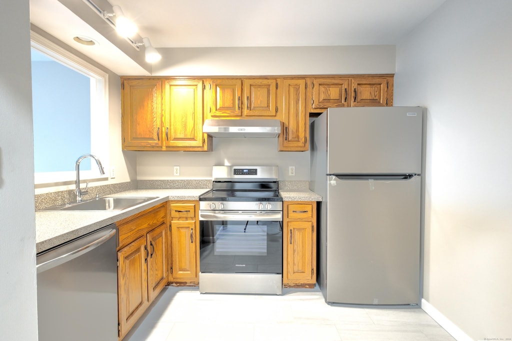 kitchen with light stone countertops, sink, and appliances with stainless steel finishes