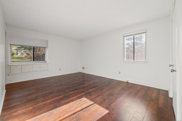 spare room with dark hardwood / wood-style flooring and a healthy amount of sunlight