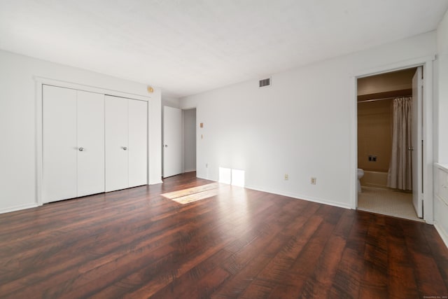 unfurnished bedroom with connected bathroom and dark hardwood / wood-style floors