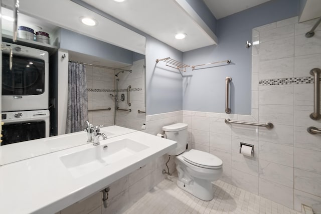 bathroom featuring tile patterned floors, a shower with curtain, stacked washer and dryer, toilet, and tile walls