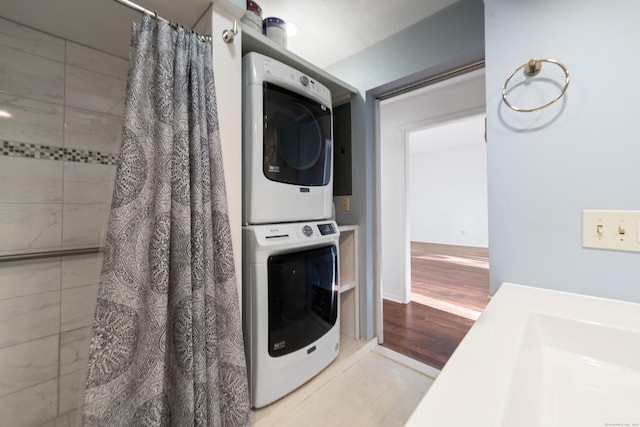 clothes washing area featuring wood-type flooring and stacked washer / dryer