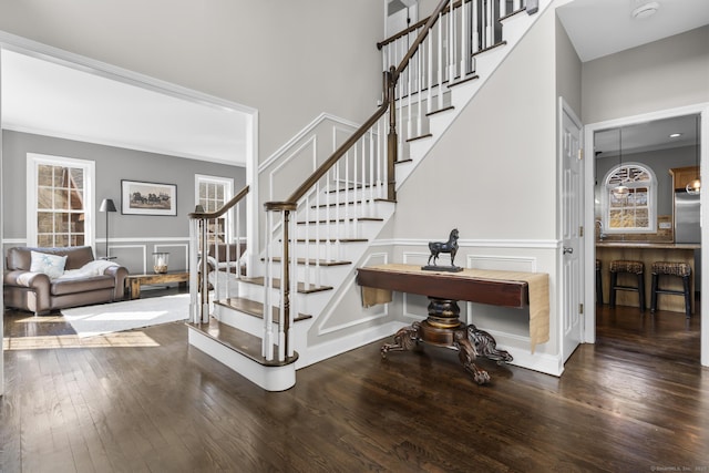 stairway with a wealth of natural light, wood-type flooring, and a decorative wall