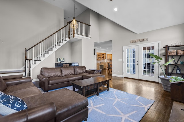 living room featuring a towering ceiling, baseboards, french doors, stairway, and hardwood / wood-style floors