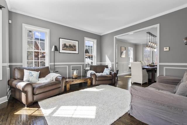 living area featuring dark wood-style floors, a decorative wall, wainscoting, and crown molding