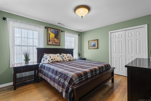 bedroom featuring light wood-type flooring, baseboards, visible vents, and a closet