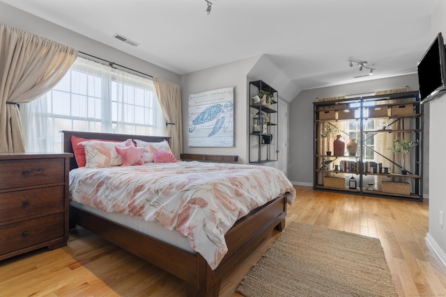 bedroom with light wood finished floors, baseboards, and visible vents