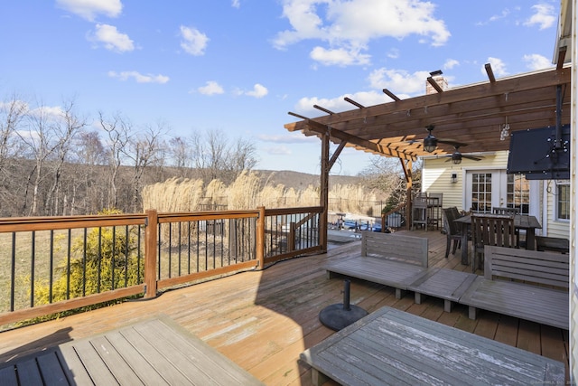 wooden deck with outdoor dining area, ceiling fan, and a pergola