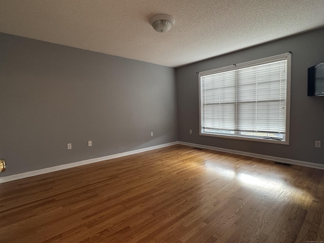 spare room featuring wood-type flooring and a textured ceiling