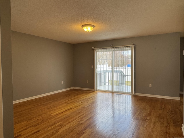 empty room with a textured ceiling and hardwood / wood-style flooring