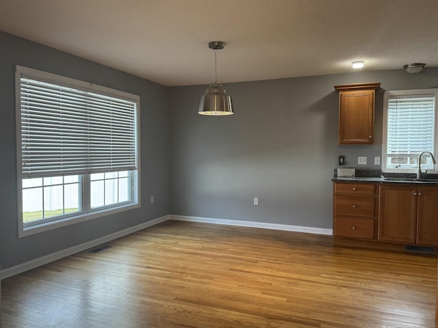 kitchen with hanging light fixtures, sink, light hardwood / wood-style floors, and a textured ceiling