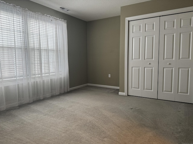 unfurnished bedroom with light carpet, a closet, and a textured ceiling