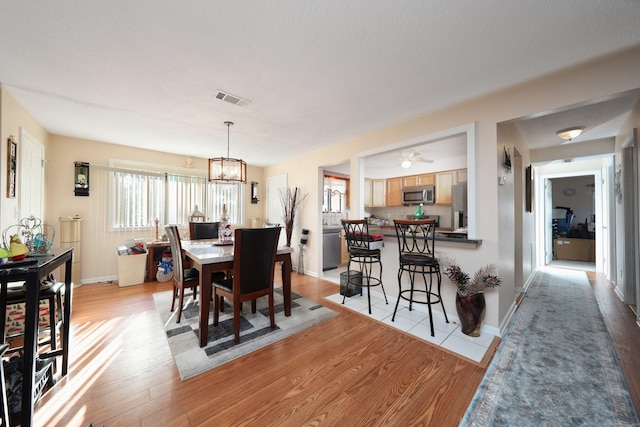 dining space featuring ceiling fan with notable chandelier and light hardwood / wood-style flooring