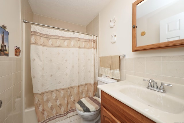 bathroom with a textured ceiling, vanity, toilet, and tile walls