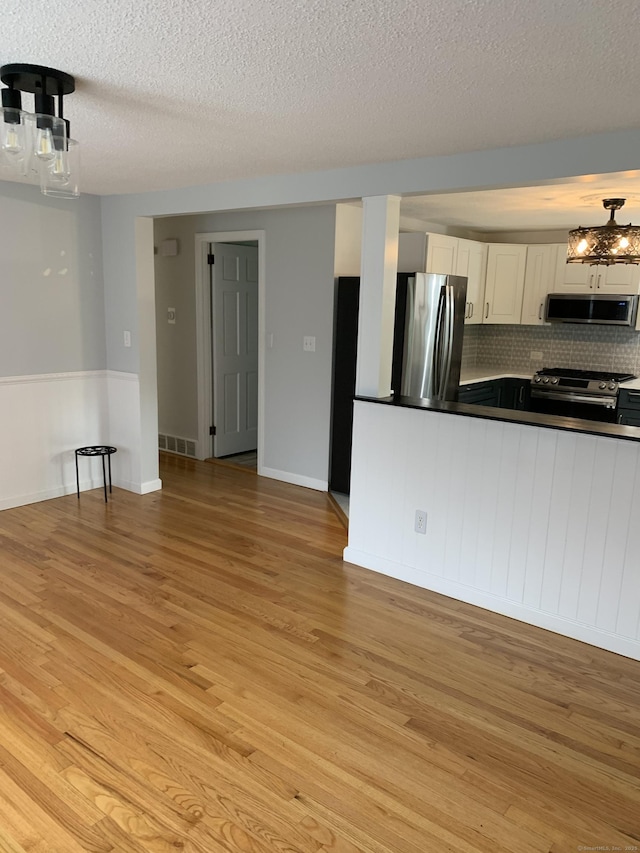 31 Gary Dr, Enfield, CT 06082 - kitchen featuring appliances with stainless steel finishes, extractor fan, dark countertops, light wood-type flooring, and a textured ceiling