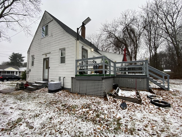 snow covered rear of property featuring a deck