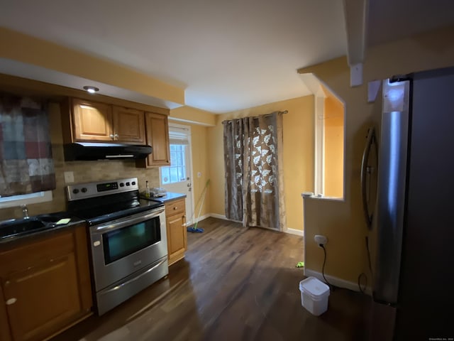 kitchen with backsplash, dark hardwood / wood-style flooring, stainless steel appliances, and extractor fan