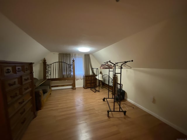 workout area with light hardwood / wood-style flooring and vaulted ceiling