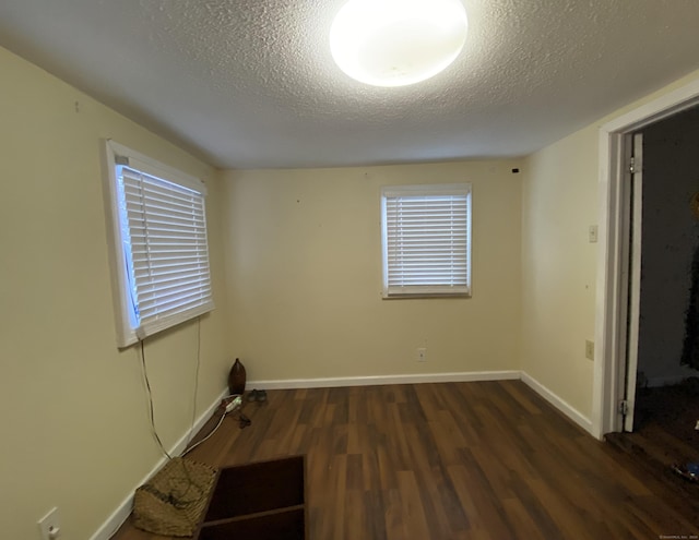 spare room with dark hardwood / wood-style flooring and a textured ceiling