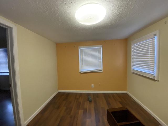 spare room featuring a textured ceiling and dark hardwood / wood-style floors