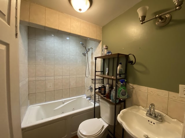 full bathroom with tiled shower / bath combo, toilet, tile walls, and sink