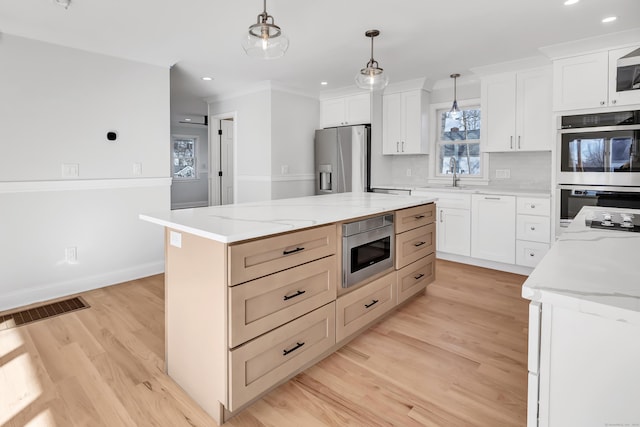 kitchen with white cabinetry, a kitchen island, pendant lighting, and appliances with stainless steel finishes