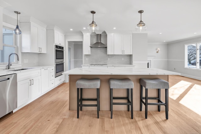 kitchen with wall chimney exhaust hood, a kitchen island, white cabinetry, and sink