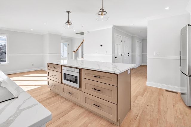 kitchen featuring stainless steel refrigerator, a center island, crown molding, decorative light fixtures, and light wood-type flooring