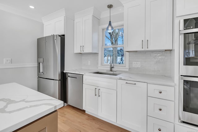 kitchen featuring hanging light fixtures, sink, white cabinets, and stainless steel appliances