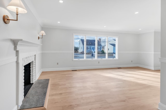 unfurnished living room with crown molding, light wood-type flooring, and a brick fireplace