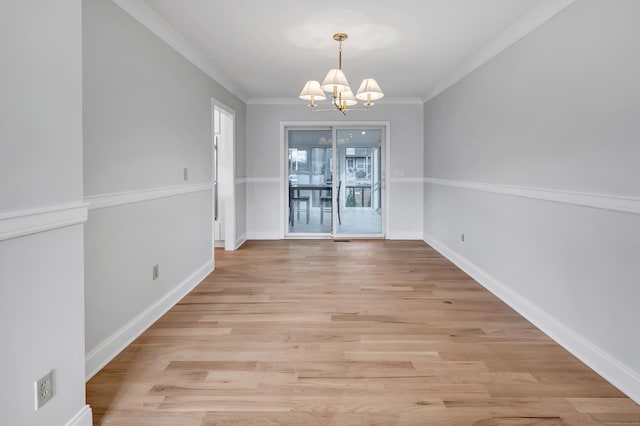 unfurnished dining area featuring crown molding, light wood-type flooring, and an inviting chandelier