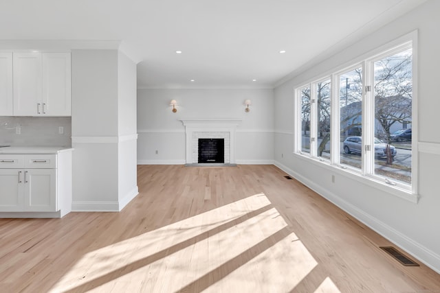 unfurnished living room featuring light hardwood / wood-style floors, ornamental molding, and a fireplace