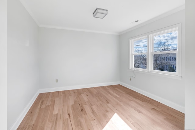 empty room featuring light wood-type flooring and crown molding