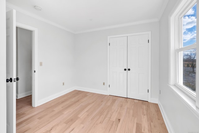 unfurnished bedroom featuring multiple windows, a closet, light hardwood / wood-style flooring, and ornamental molding